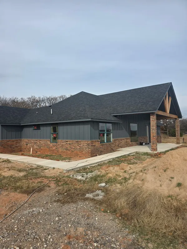 Dark gray home with stone base and timber gable