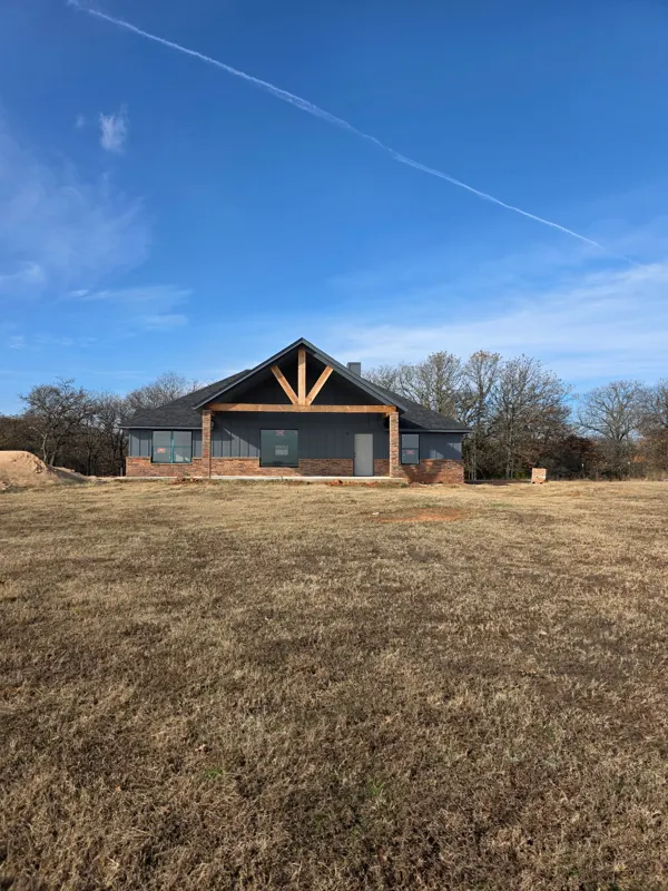 Dark-roof home with timber gable entry on open land