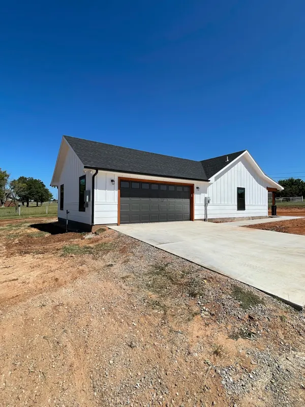 White farmhouse with black garage door and driveway